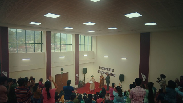 Video Reference: Chair, Building, Leisure, T-shirt, Event, Hall, Academic institution, Room, Crowd, Ceiling