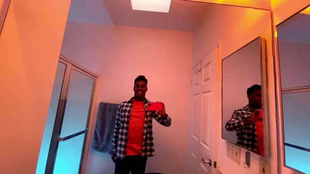 Video Reference: Outerwear, Shirt, Textile, Orange, Sleeve, Standing, Lighting, Eyewear, Interior design, Yellow