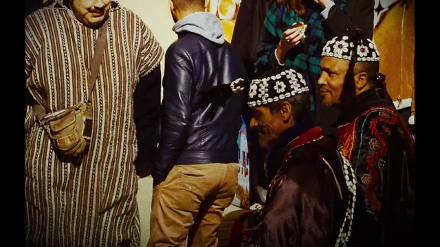 Video Reference: Outerwear, Human, Cap, Sleeve, Headgear, Hat, Street fashion, People, Leather jacket, Event