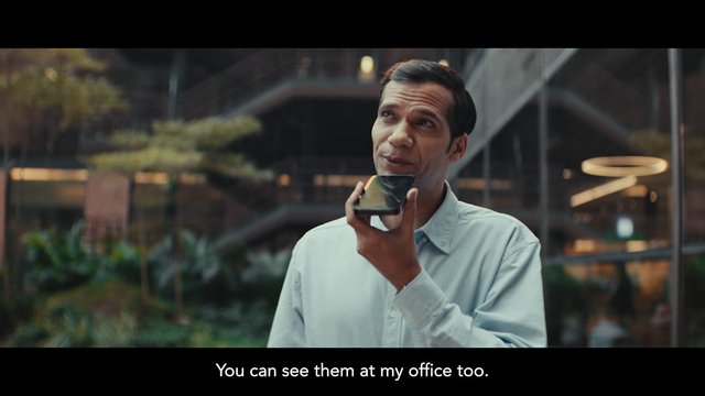 Video Reference: man, smartphone, office, indoor, atrium, business, portrait, subtitles, modern interior, holding phone, conversation, casual shirt