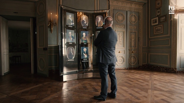 Video Reference: Suit trousers, Sleeve, Standing, Picture frame, Door, Fixture, Wood, Flooring, Blazer, Formal wear