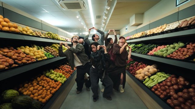Video Reference: grocery store, produce aisle, fruit, vegetables, people, posing, indoor, supermarket, apples, bananas, oranges, cucumbers, market, group, aisle, food