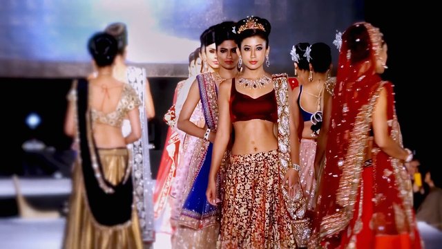 Video Reference: fashion, runway, models, catwalk, traditional dress, formal wear, jewelry, glamour, stage, event, portrait, indoor, elegant, celebration