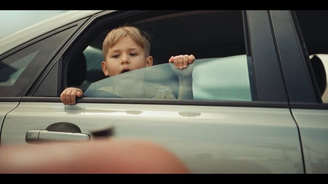 Video Reference: child, boy, car, window, vehicle, looking out, rear seat, travel, portrait, daylight, close-up, family