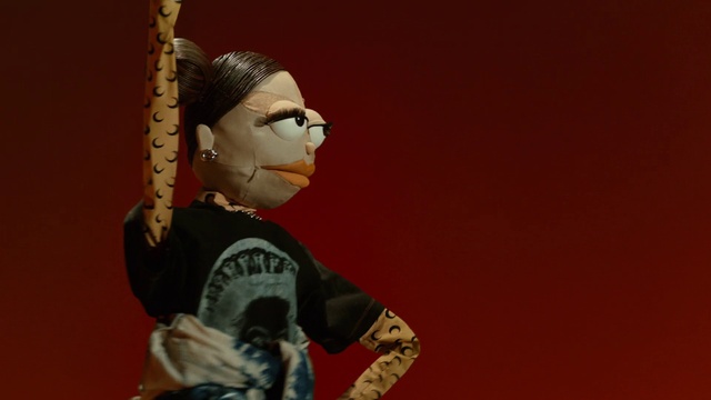 Video Reference: Head, Sleeve, Gesture, Personal protective equipment, Eyewear, Carmine, Action figure, Toy, Audio equipment, Figurine