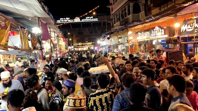 Video Reference: Infrastructure, Hat, Building, Public space, Crowd, City, Market, Metropolitan area, Baseball cap, Urban area