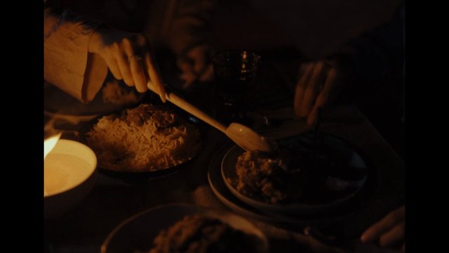 Video Reference: dinner, food, rice, table, hands, spoon, serving, meal, shared meal, dark lighting, indoor, close-up, dining, candlelight, cooked food