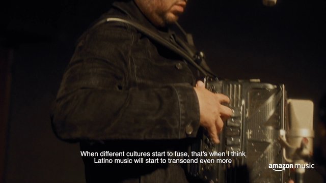 Video Reference: accordion, musician, performance, close-up, instrument, live music, dim lighting, subtitles, music video, commercial, portrait crop, indoor, hands, Latino music, Amazon Music