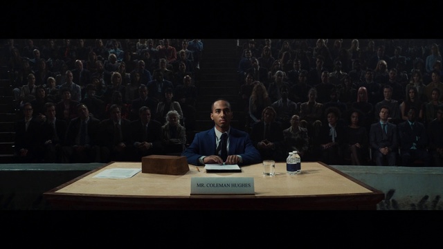Video Reference: Microphone, Table, Coat, Desk, Chair, Suit, Spokesperson, Public address system, Speaker, Public speaking