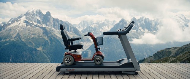 Video Reference: mobility scooter, treadmill, wooden deck, mountains, snowy peaks, clouds, outdoors, travel, landscape, side view, red scooter, wheelchair alternative, platform, scenic, alpine