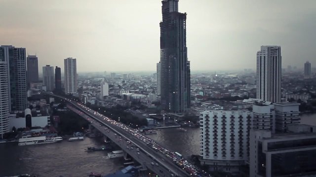 Video Reference: cityscape, skyline, bridge, traffic, river, high-rise, tower, construction, urban, haze, dusk, waterfront, metropolis, buildings, aerial view