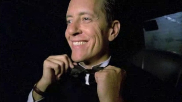 Video Reference: Cheek, Smile, Jaw, Ear, Tie, Gesture, Flash photography, Finger, Dress shirt, Bow tie