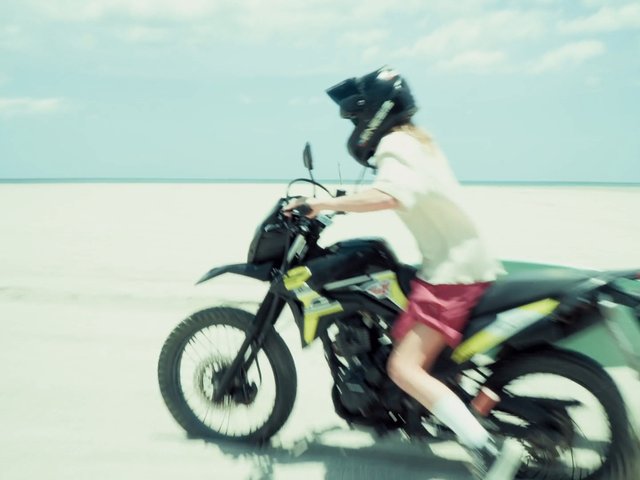 Video Reference: motorcycle, dirt bike, rider, helmet, beach, sand, motion blur, outdoors, sky, beach ride, action, vehicle, summer, coast, sport