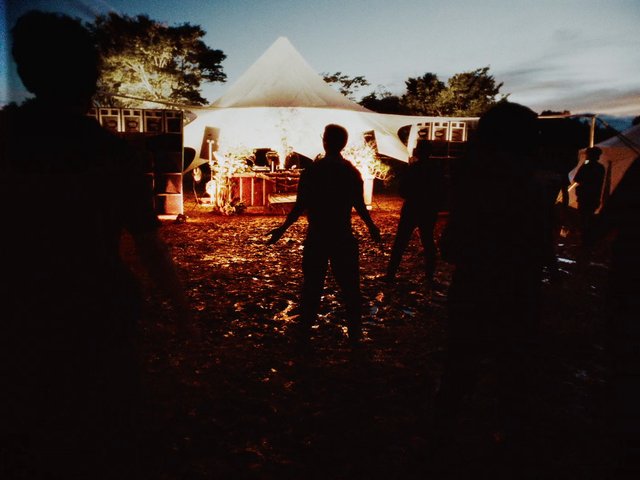 Video Reference: night, outdoor, event, tent, canopy, silhouette, people, festival, lighting, evening, gathering, stage, crowd, backlit, camping