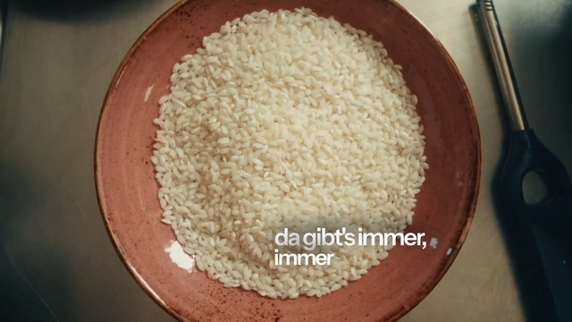 Video Reference: rice, bowl, uncooked, kitchen, food, ingredient, top view, cooking, utensil, overhead, grain, recipe, close-up, text overlay, German