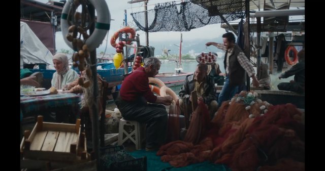 Video Reference: dock, harbor, boats, fishing nets, life ring, people, outdoor dining, waterfront, seaside, market, ropes, nets, boatyard, workshop, table, overcast