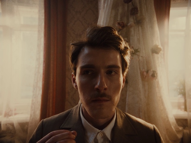 Video Reference: Forehead, Eyebrow, Dress shirt, Flash photography, Jaw, Gesture, Curtain, Collar, Tie, Blazer