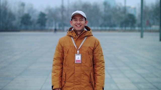 Video Reference: Smile, Outerwear, Street fashion, Sleeve, Happy, Cap, Asphalt, Travel, Electric blue, Road