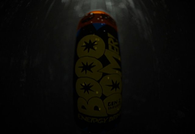 Video Reference: can, bottle, close-up, dark, abstract, graphic design, packaging, product, beverage, label, yellow, orange, black, low light, still life