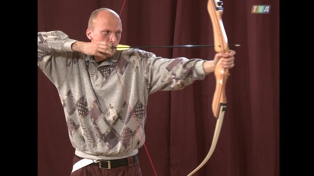 Video Reference: archery, man, bow, arrow, aiming, sports, indoor, target practice, curtain, close-up, training, competition