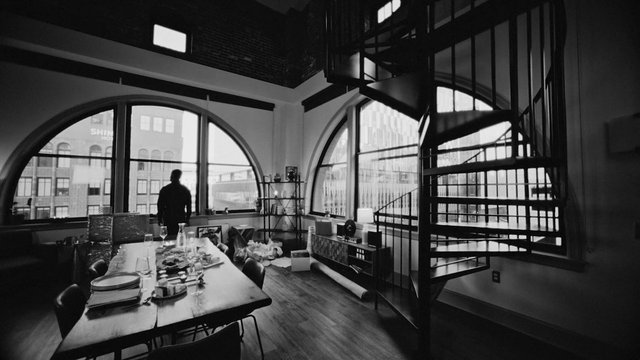 Video Reference: black and white, interior, loft, dining room, spiral staircase, arched windows, urban view, table, person silhouette, modern design, architecture, wide angle, home, office, natural light, city