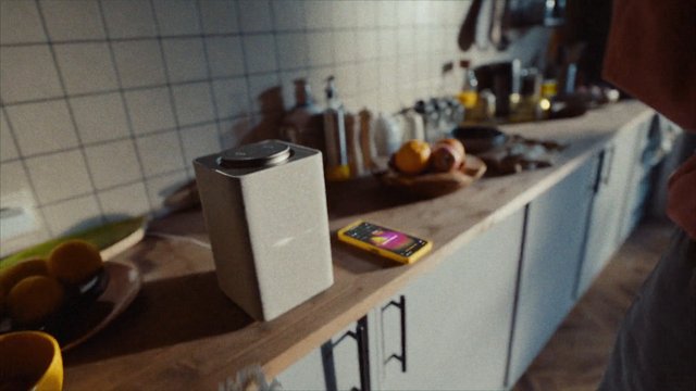 Video Reference: kitchen, countertop, speaker, smartphone, fruit, utensils, indoor, home, appliance, tabletop, still life, modern, casual, blurred background