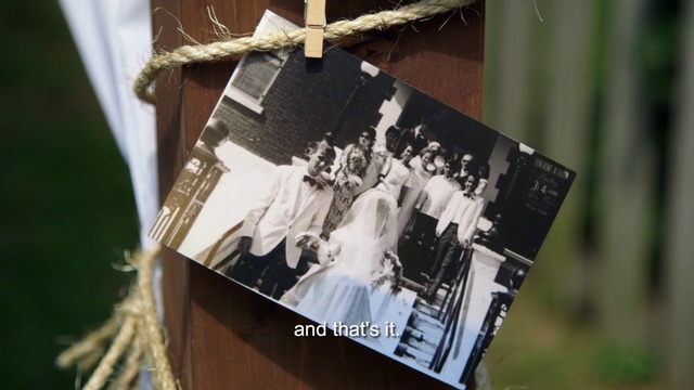 Video Reference: Dress, Bridal clothing, Suit, Wedding dress, Font, Event, Rectangle, Formal wear, Wood, Bride