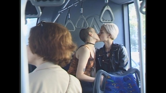 Video Reference: bus, tram, public transport, kissing, couple, interior, passengers, hand straps, travel, urban, young adults, leather jacket, short hair, window, commuter, romantic