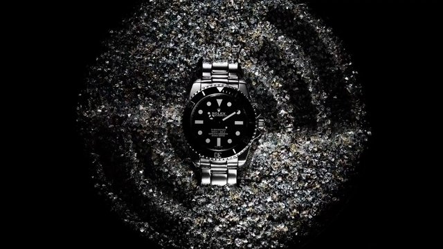 Video Reference: wristwatch, silver watch, black dial, luxury watch, close-up, product shot, studio lighting, metal bracelet, timepiece, fashion accessory, dark background, sparkling texture