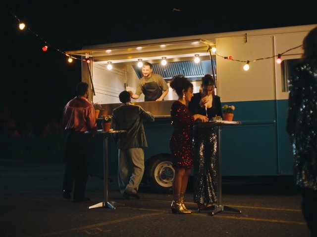Video Reference: food truck, night, outdoor event, party, vendor, serving food, string lights, cocktail tables, guests, street food, social gathering, evening, drinks, casual dining