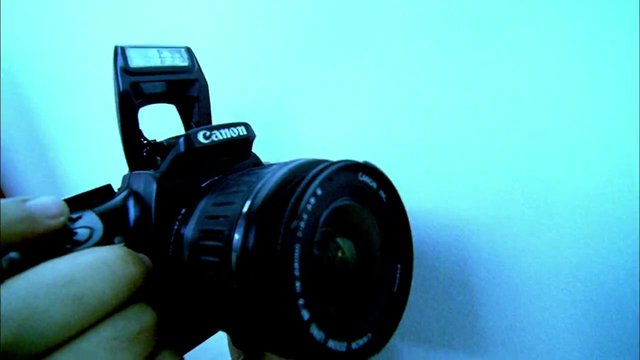 Video Reference: camera, DSLR, Canon, close-up, handheld, lens, photography, equipment, device, electronics, blue background, studio-like, single object, macro, brand logo