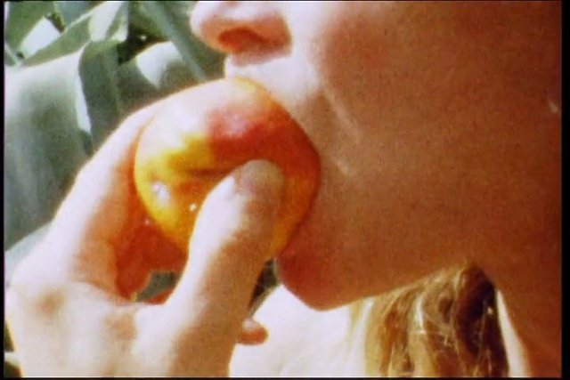 Video Reference: close-up, person, eating, fruit, peach, nectarine, bite, hand, mouth, food, snack, indoor, casual