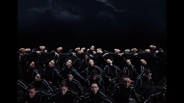 Video Reference: dancers, group performance, choreography, stage, dark background, matching outfits, synchronized, theater, artistic, movement, performance art, dance ensemble, low light, abstract