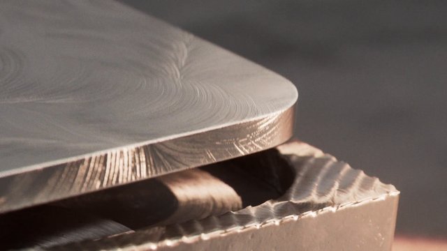 Video Reference: metalworking, machining, milling, cutting, tool, metal block, industrial, close-up, rotation, shavings, surface finish, manufacturing, precision, workshop