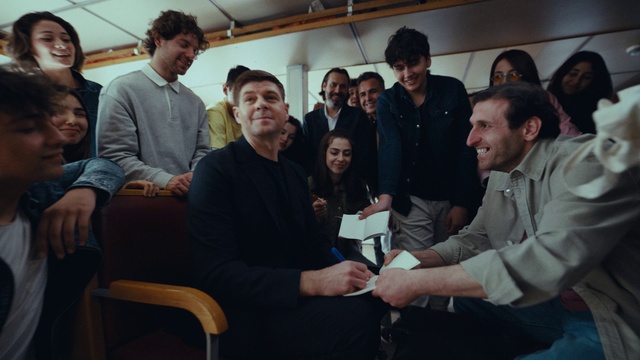 Video Reference: Face, Smile, Shirt, Chair, Jacket, Event, Crowd, White-collar worker, Team, T-shirt
