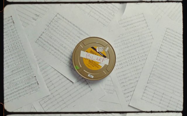 Video Reference: sheet music, music score, paper, film canister, top view, still life, scattered pages, vintage, archive, music, overhead, prop, label, studio