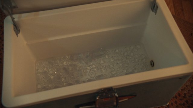 Video Reference: cooler, ice, ice cubes, storage box, container, open lid, water, indoor, top view, beverage cooler, cold, white box