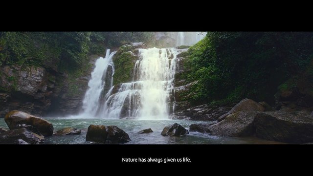 Video Reference: waterfall, nature, forest, rocks, river, landscape, outdoors, scenic, lush, cascade, pool, greenery, mist, wilderness, subtitle, wide shot