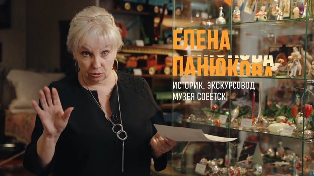 Video Reference: woman, museum, exhibit, speaker, portrait, interior, glass display, decorative objects, Cyrillic text, documentary, guide, historian, interview, gesturing, indoors