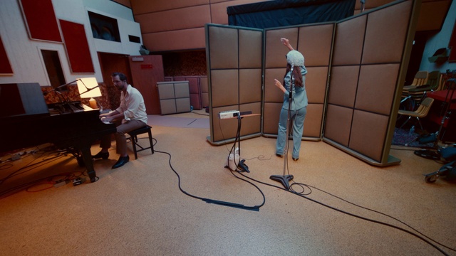 Video Reference: Building, Tripod, Piano, Flooring, Floor, Musical instrument, Audio equipment, Wood, Musical keyboard, Couch