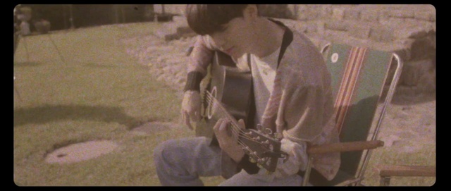 Video Reference: Guitar accessory, Musical instrument, Guitar, Font, String instrument accessory, Darkness, Event, Plucked string instruments, Room, Music