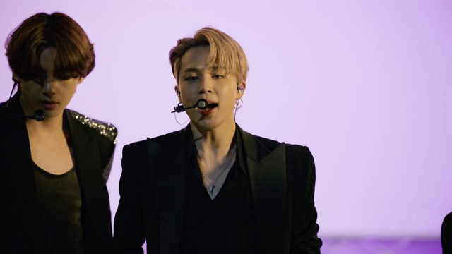 Video Reference: Hair, Eyelash, Microphone, Lipstick, Neck, Coat, Gesture, Flash photography, Fashion design, Audio equipment