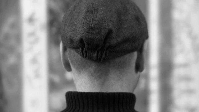 Video Reference: black and white, rear view, person, cap, flat cap, sweater, close up, portrait, blurred background, monochrome, back of head, outdoor, minimal, shallow depth of field