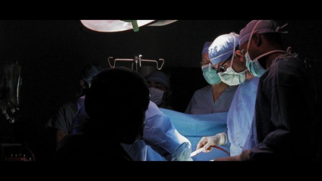 Video Reference: operating room, surgeons, surgery, medical team, hospital, sterile, scrubs, masks, procedure, patient care, operating table, healthcare, clinical, dramatic lighting