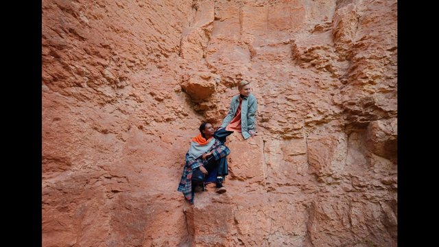 Video Reference: canyon, rock wall, sandstone, cliff, hiking, outdoors, two people, ledge, adventure, nature, desert, rock formation, travel, standing, sitting