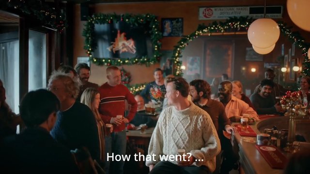 Video Reference: bar, pub, party, people, socializing, festive, holiday decorations, drinks, interior, group, conversation, celebration, warm lighting, subtitle, crowd
