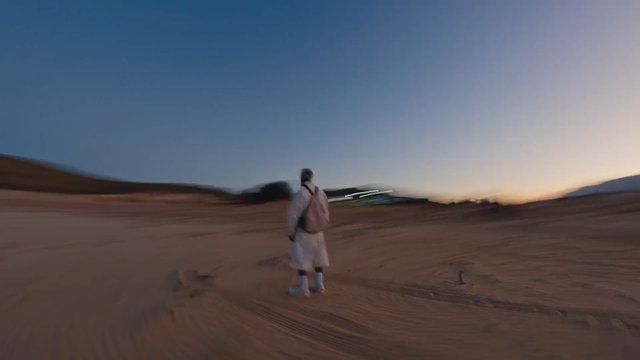 Video Reference: desert, dusk, person, standing, landscape, sand, sky, outdoors, travel, motion blur, backpack, evening, wilderness, alone