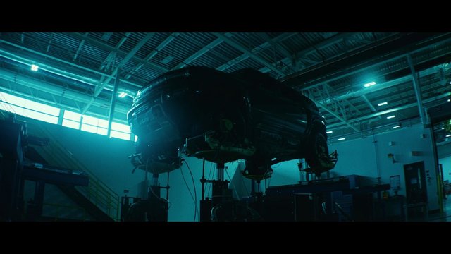 Video Reference: industrial, warehouse, workshop, machine, vehicle, suspended, support stands, ceiling beams, overhead lights, equipment, mechanical, factory, indoor, dark, blue lighting