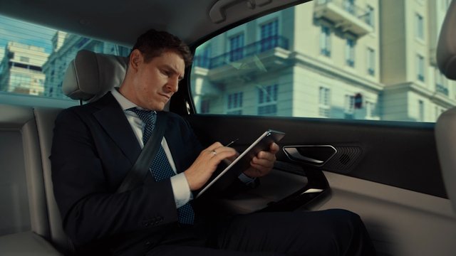 Video Reference: businessman, car interior, tablet, suit, commuting, urban, back seat, professional, mobile office, city, travel, executive, work