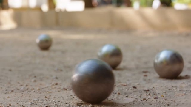Video Reference: metal balls, boules, petanque, bocce, sports, outdoor, sand, game, close-up, shallow depth of field, blurred background, recreation